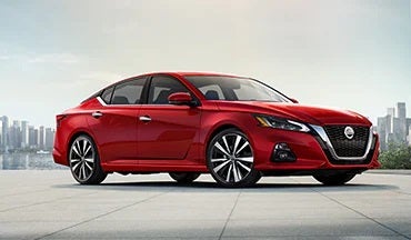 2023 Nissan Altima in red with city in background illustrating last year's 2022 model in Crossroads Nissan Wake Forest in Wake Forest NC